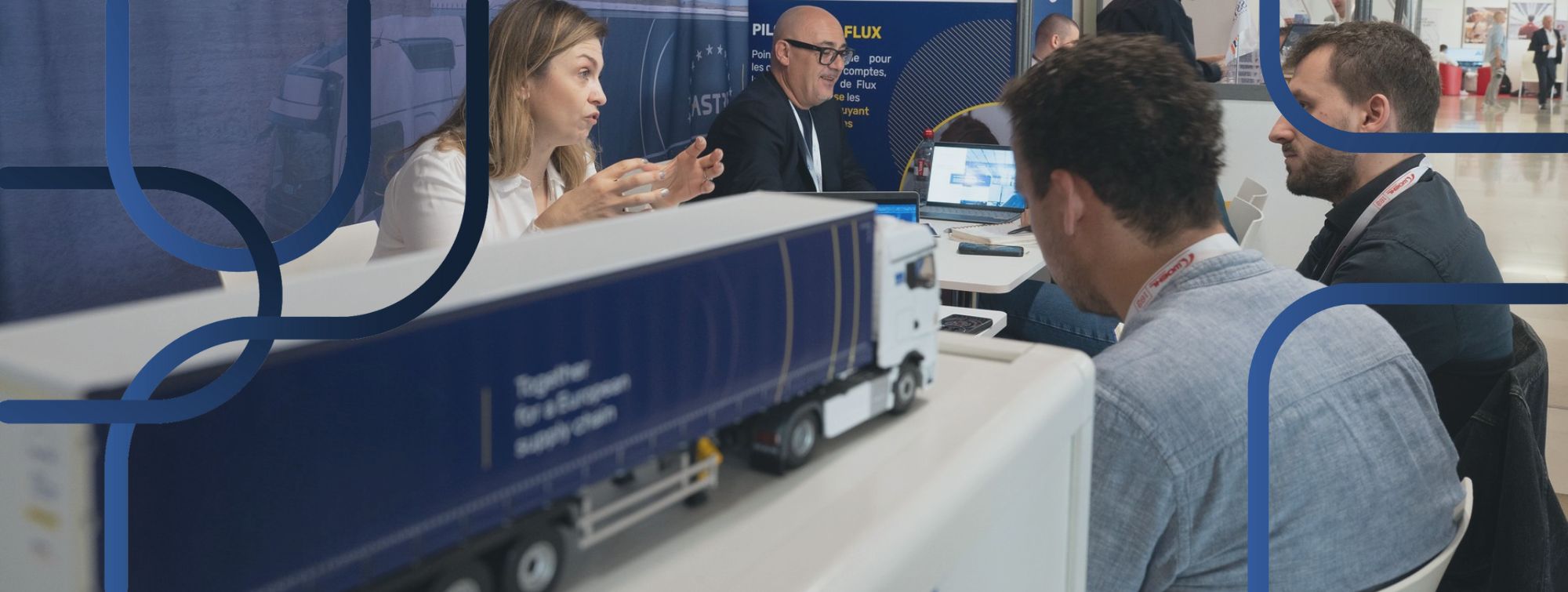 une femme et des hommes discutant autout d'une table, avec un camion au premier plan