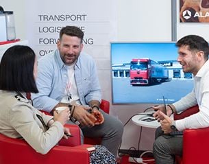 Two men and a woman sitting in front of a screen with a truck