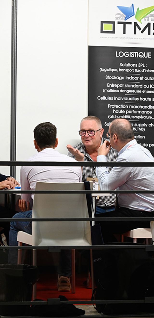 Groupe d'hommes assis à une table derrière une barrière