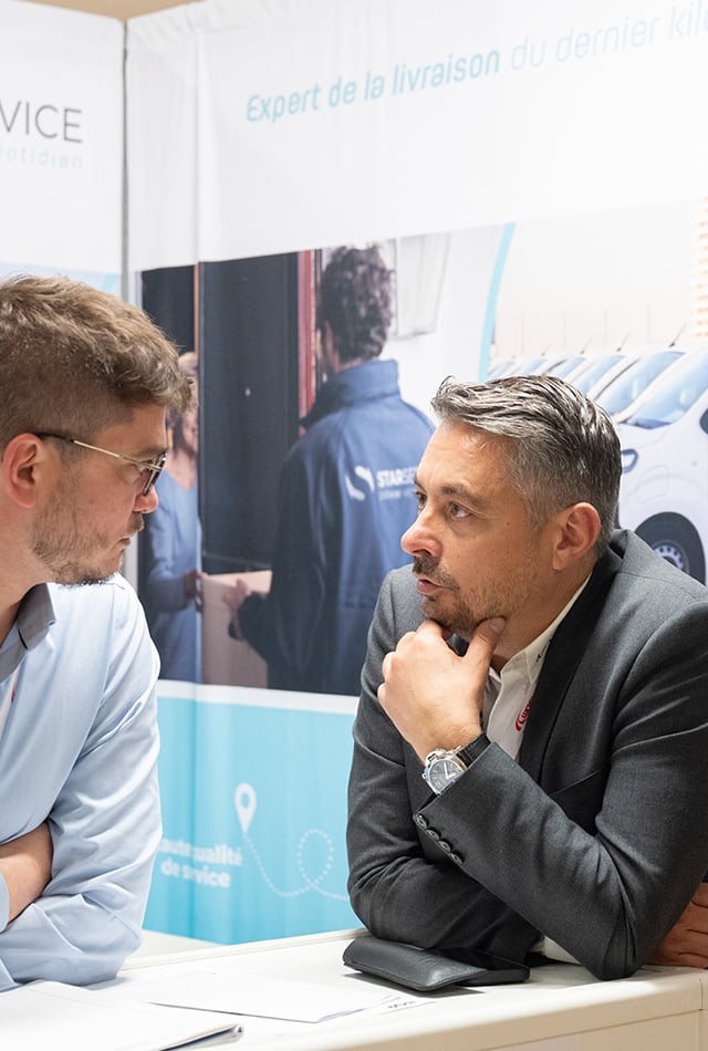 Deux hommes face à face devant une affiche avec un livreur