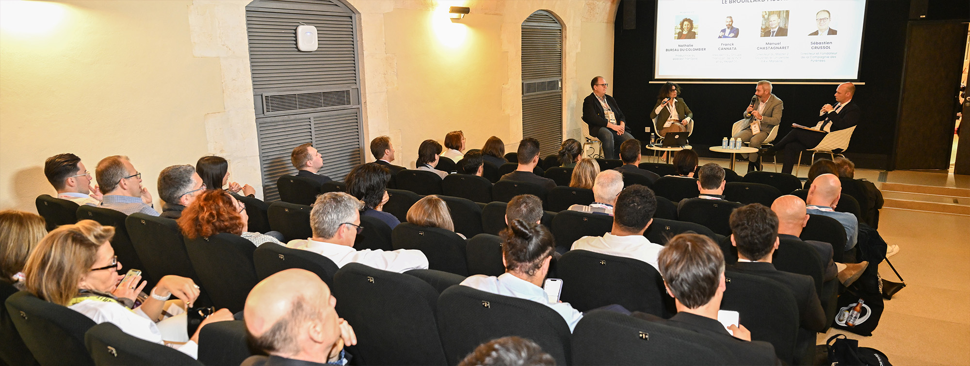 Public regardant un écran lors d'une conférence