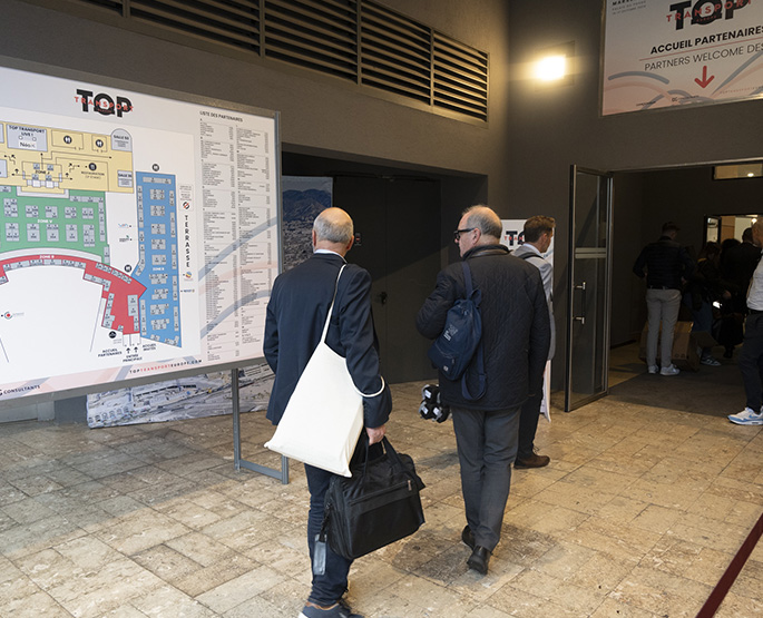 Visitors with bags in front of the exhibition plan