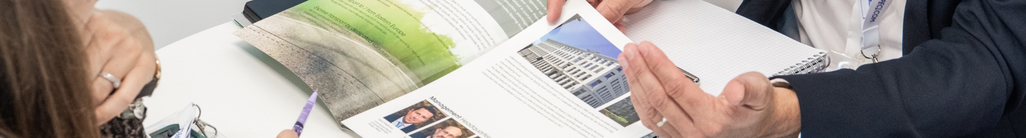 Deux participants examinant une brochure et discutant des contenus à Top Transport Europe.